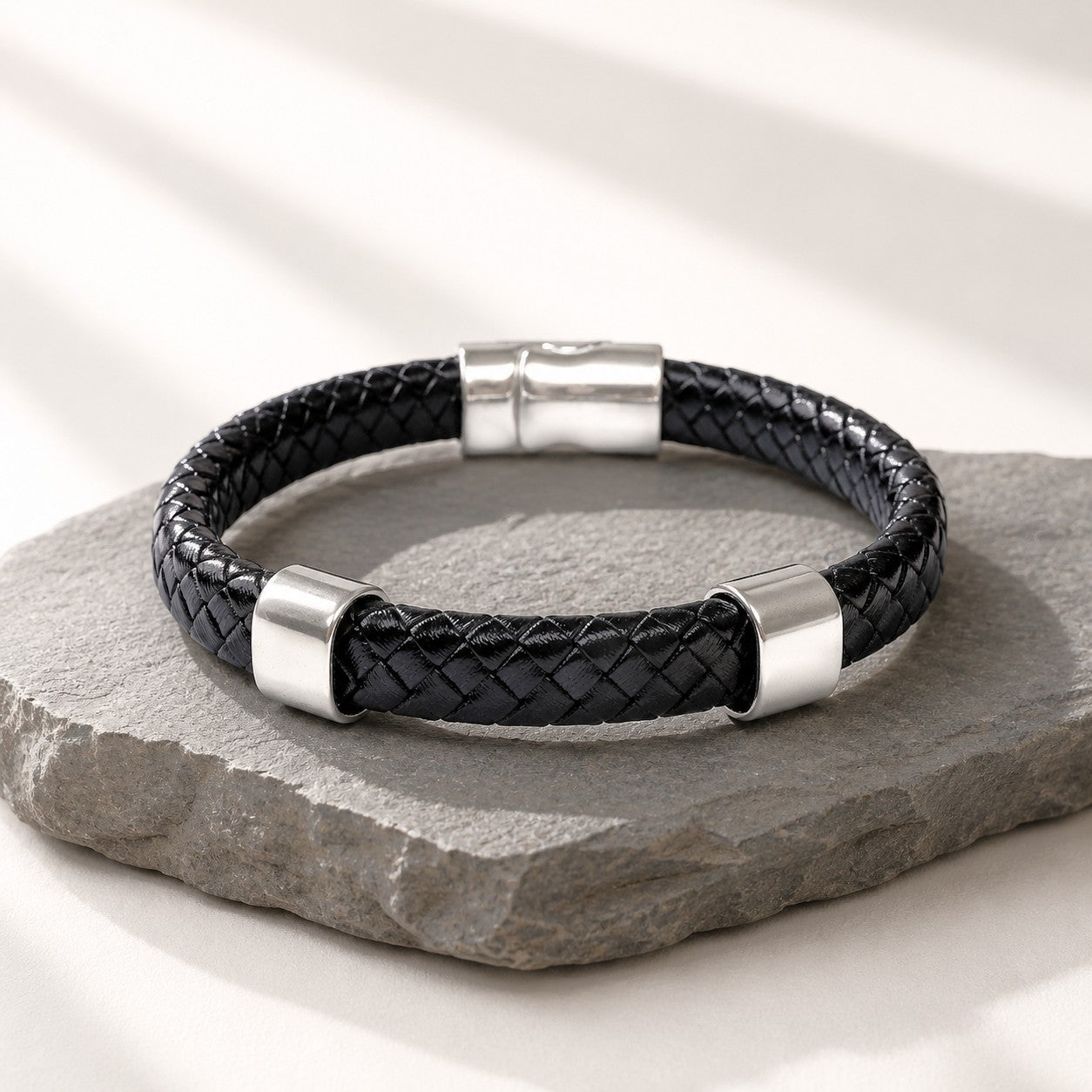 Black braided leather bracelet with a polished silver magnetic clasp and two silver engravable slider charms. Minimalist unisex bracelet handcrafted from genuine braided leather, featuring a sleek modern design suitable for everyday wear, gifts, anniversaries, and personalized engraving.
