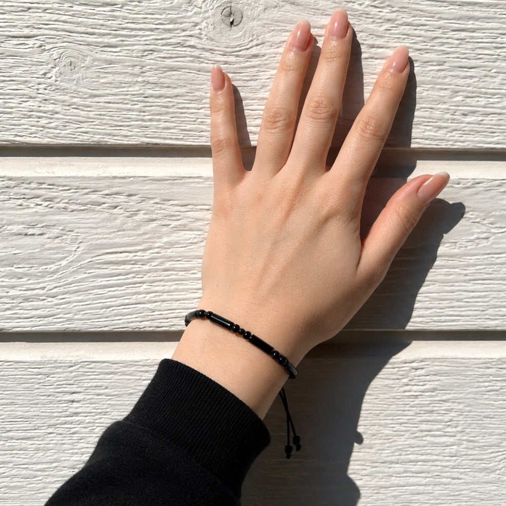 Black onyx tube bead bracelet worn on wrist showing adjustable fit, waterproof minimalist gemstone bracelet for men and women