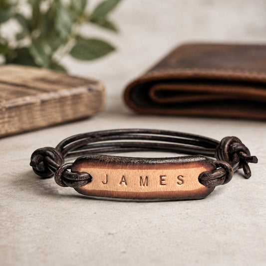 Personalized men's leather bracelet featuring a hand-stamped copper nameplate engraved with "JAMES" on dark brown adjustable leather cords. Handmade custom name bracelet with rustic copper tag, minimalist masculine design, and adjustable fit. Meaningful personalized gift for husband, boyfriend, dad, son, anniversary, birthday, Father's Day, graduation, or Christmas.