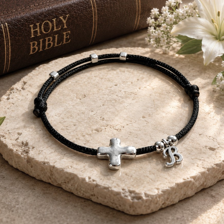 Handmade black satin nylon cord bracelet featuring a silver-plated sideways cross and optional initial charm. The bracelet includes sliding knots for adjustability and small silver accent beads. Bracelet is lightweight, waterproof, and ideal for daily wear. This unisex Christian bracelet is a meaningful religious gift, available in various sizes for men, women, and children. Make it a great Faith gift for any ocations.