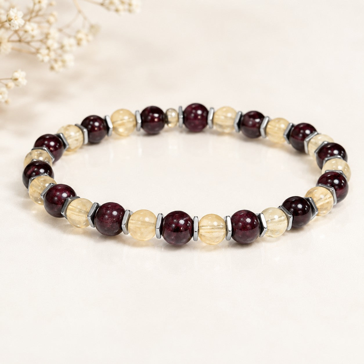 Handcrafted citrine and garnet stretch bracelet featuring alternating round beads of golden-yellow citrine and deep red garnet, separated by slim metallic hematite spacers. The bracelet is strung on a durable elastic cord for a comfortable, flexible fit. Displayed on a clean white background with subtle shadow, the contrasting warm and rich gemstone colors make this bracelet a bold yet elegant accessory for everyday wear or special occasions.