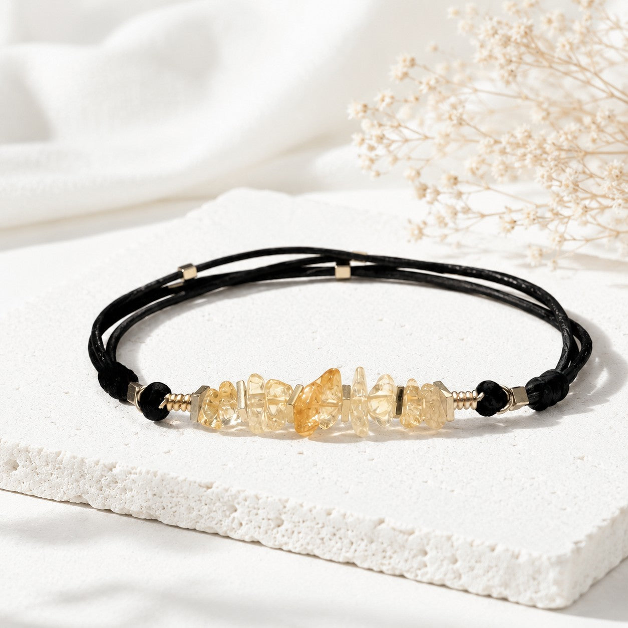 Handmade adjustable citrine bracelet featuring natural golden-yellow citrine gemstone chips accented with gold hematite spacer beads on a double black leather cord. The bracelet is minimalist and elegant, symbolizing positivity, success, and good fortune. Displayed on a clean white background with soft shadows, the bracelet’s warm tones and natural textures stand out beautifully.