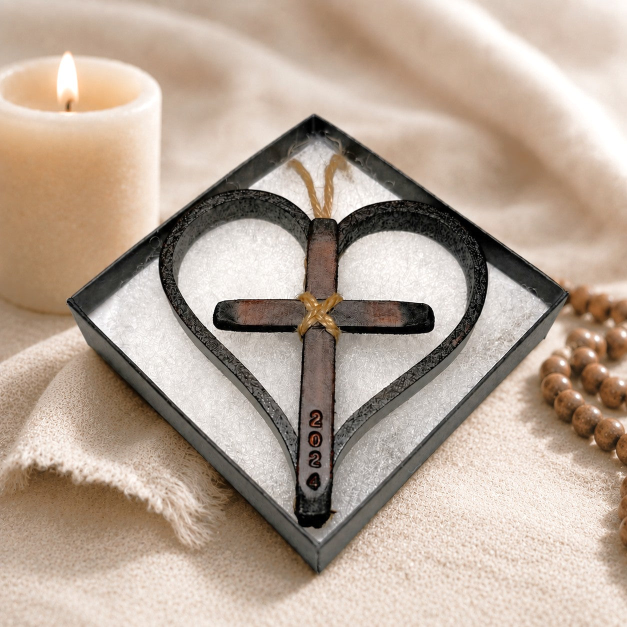 Personalized leather and twine Christian ornament featuring a handcrafted heart-shaped natural leather frame surrounding a rustic wooden cross. The cross is secured with natural jute twine and stamping creating a meaningful keepsake for faith-based celebrations. The ornament hangs from a twine loop and is displayed against a soft neutral background. Measuring approximately 3.5 inches by 3.5 inches, this handmade religious ornament is ideal for Christmas trees, rearview mirrors, anniversary.
