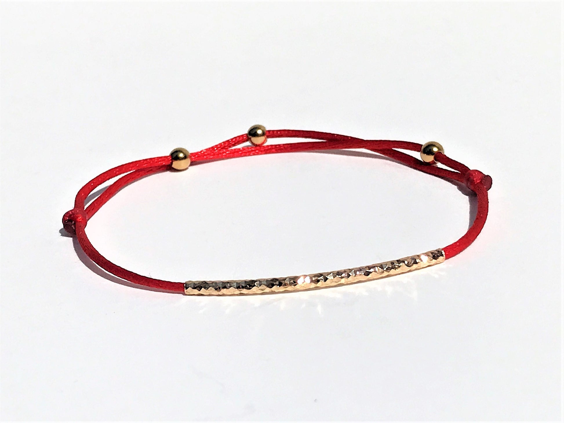 Handcrafted Adjustable Tiny Red String Bracelet for Good Luck. It features a silky red string complemented by a faceted gold tube and 3 delicate beads.