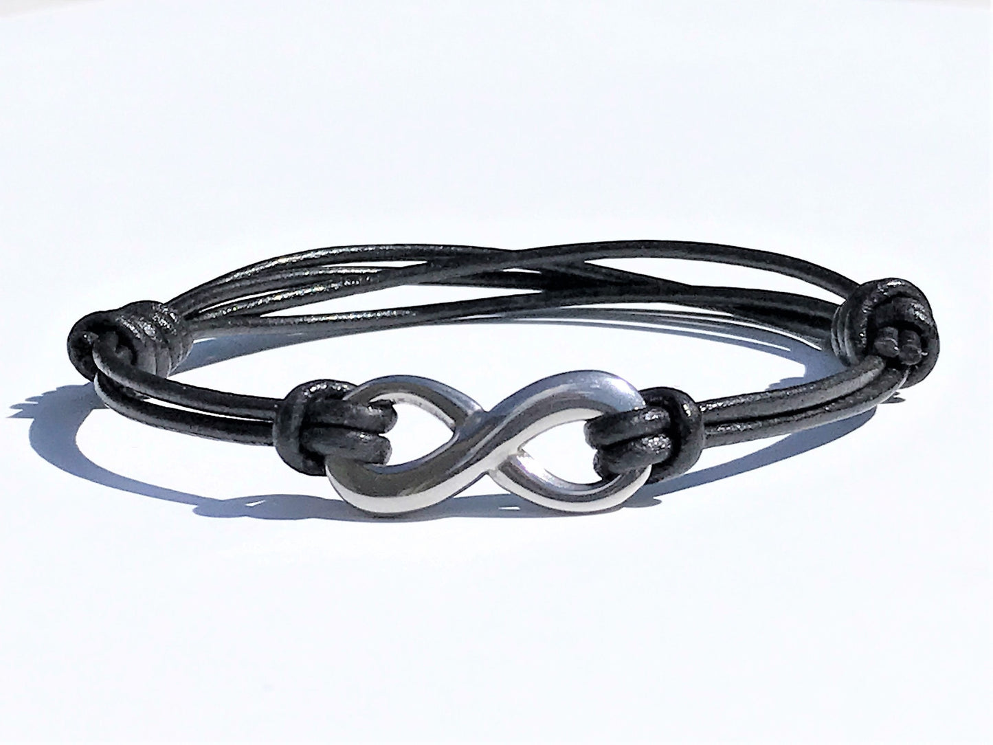 Black Leather Cord Bracelet with Stainless Steal Infinity Charm for Men and Women. Bracelet is adjustable with sliding knots on both sides of the Infinity. Great gift for the 3rd Anniversary for Men and Women.