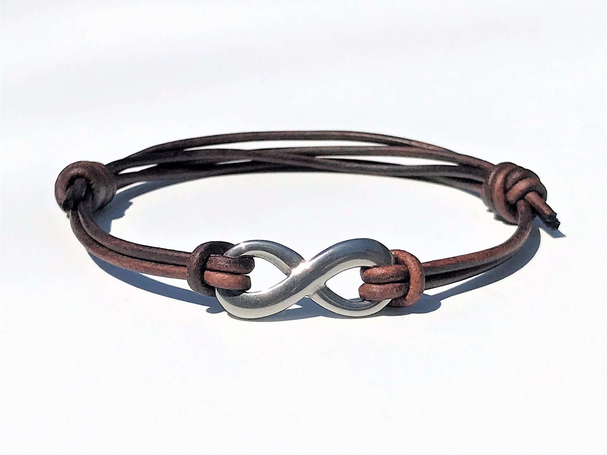 Distressed Brown Leather Cord Bracelet with Stainless Steal Infinity Charm. Bracelet is easily adjustable with sliding knots. Great gift for the 3rd Anniversary for Men and Women.