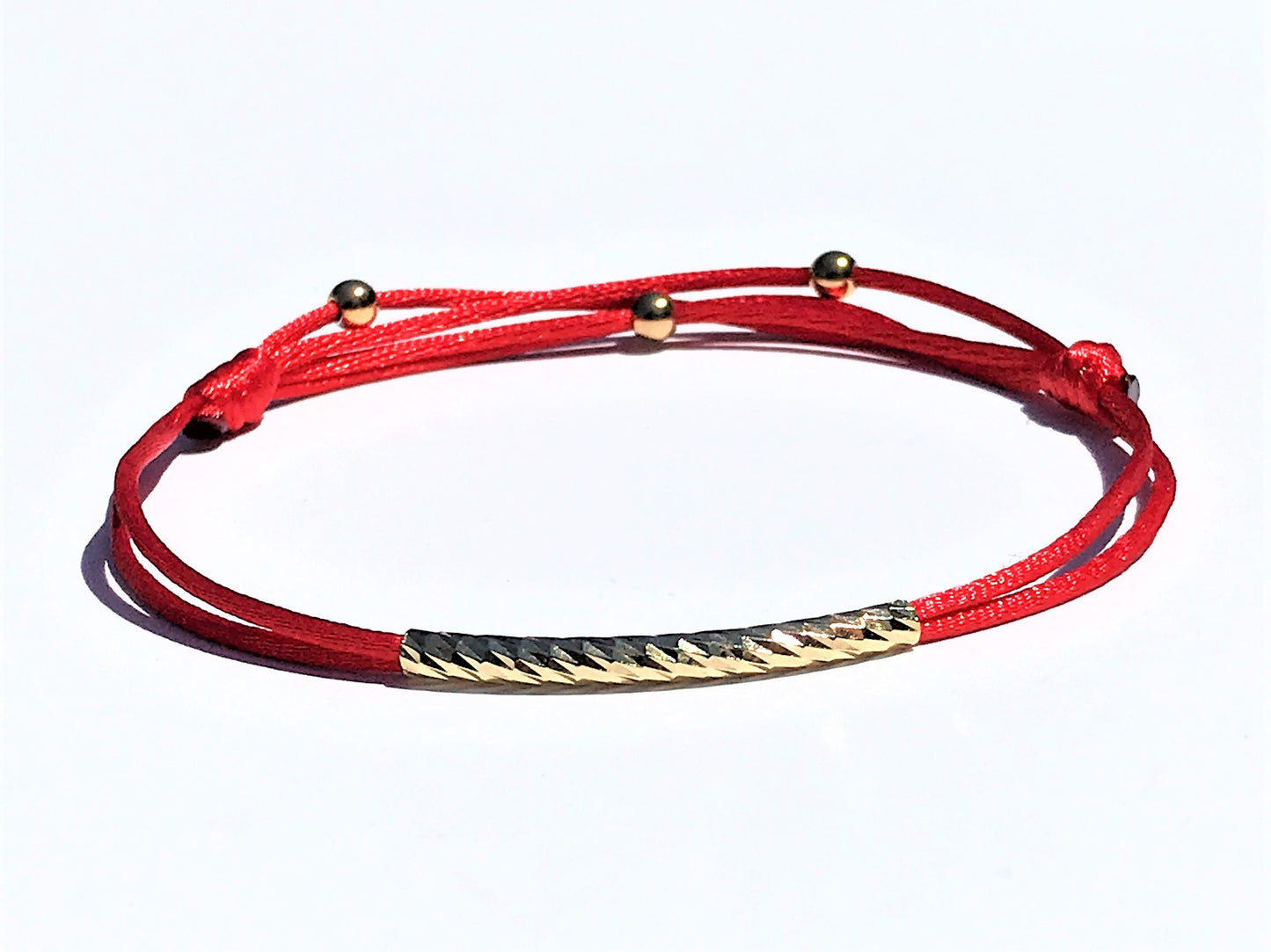 Handcrafted Adjustable Tiny Red String Bracelet for Good Luck. It features a silky red string complemented by a faceted gold tube and three delicate beads. 