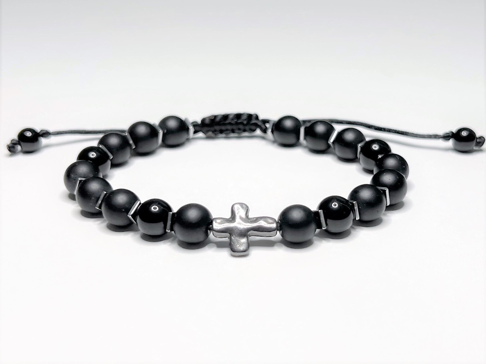 Adjustable black onyx beaded bracelet with silver hematite spacers and a central silver cross on a macramé nylon cord.