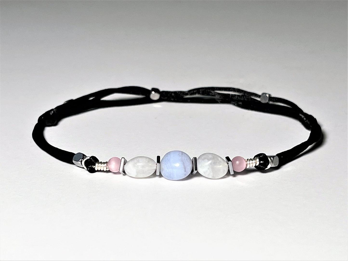 Moonstone and Blue Lace Agate gemstones anklet. The anklet is made with silky black string and adjustable for a perfect size.  
One Blue Lace Agate surrounds smaller moonstone gemstones. In between gemstones are square flat Hematite silver beads.