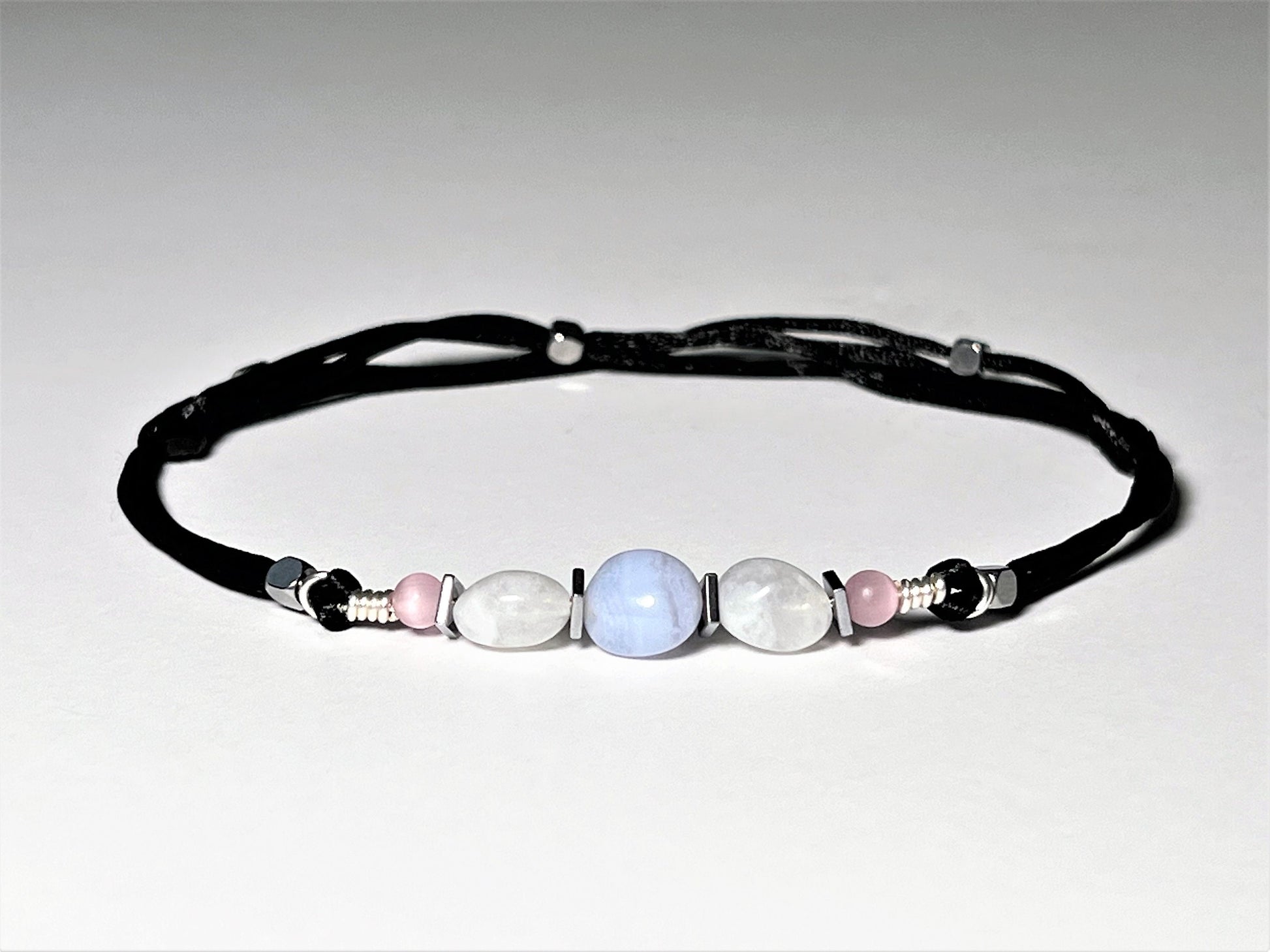 Moonstone and Blue Lace Agate gemstones anklet. The anklet is made with silky black string and adjustable for a perfect size.  
One Blue Lace Agate surrounds smaller moonstone gemstones. In between gemstones are square flat Hematite silver beads.