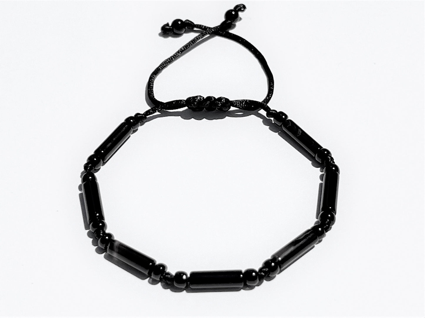 Close-up of handmade black onyx bracelet showing polished tube beads, round spacers, and adjustable sliding knot closure