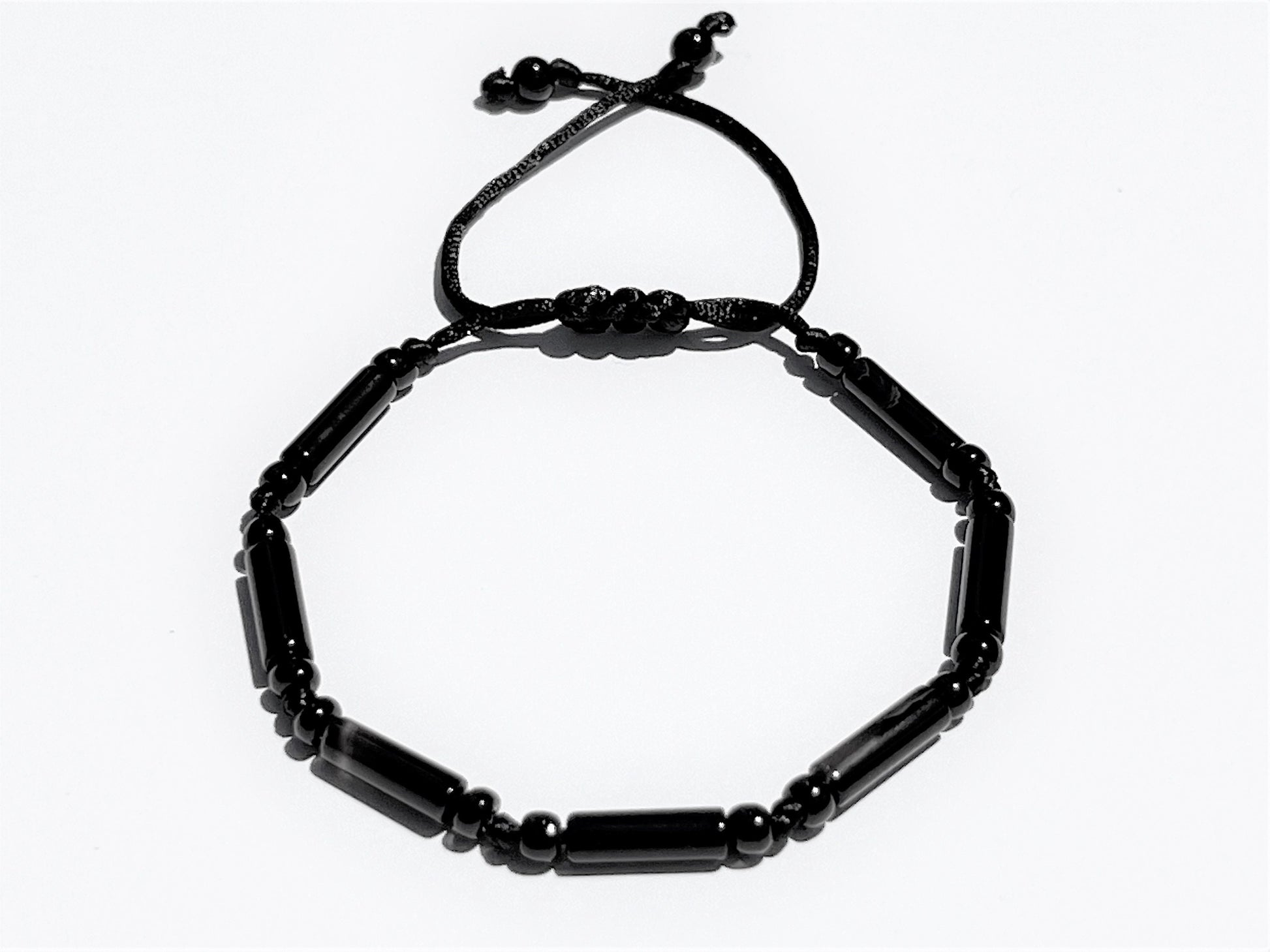 Close-up of handmade black onyx bracelet showing polished tube beads, round spacers, and adjustable sliding knot closure