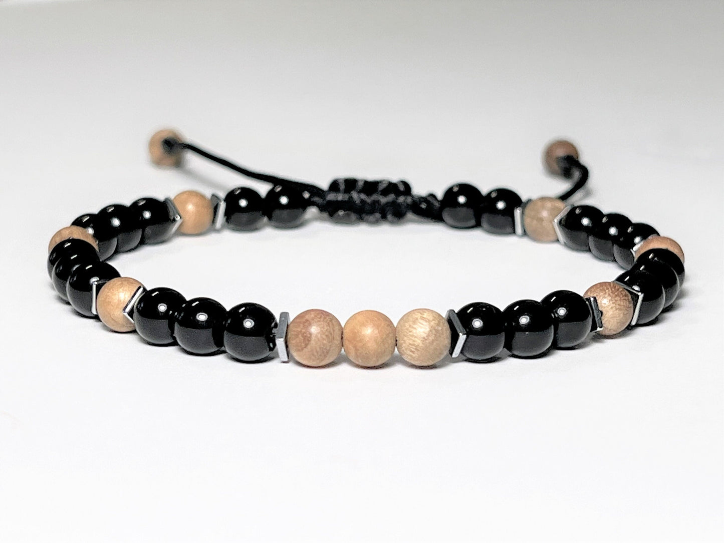 Round beaded Sandalwood Bracelet with black Onyx and a touch of Hematite square flat beads around Sandalwood beads. Round beads are 6mm. Waterproof and easily adjustable with a sliding macrame clasp. Round beads are 6 mm. Great gift for Boyfriend.