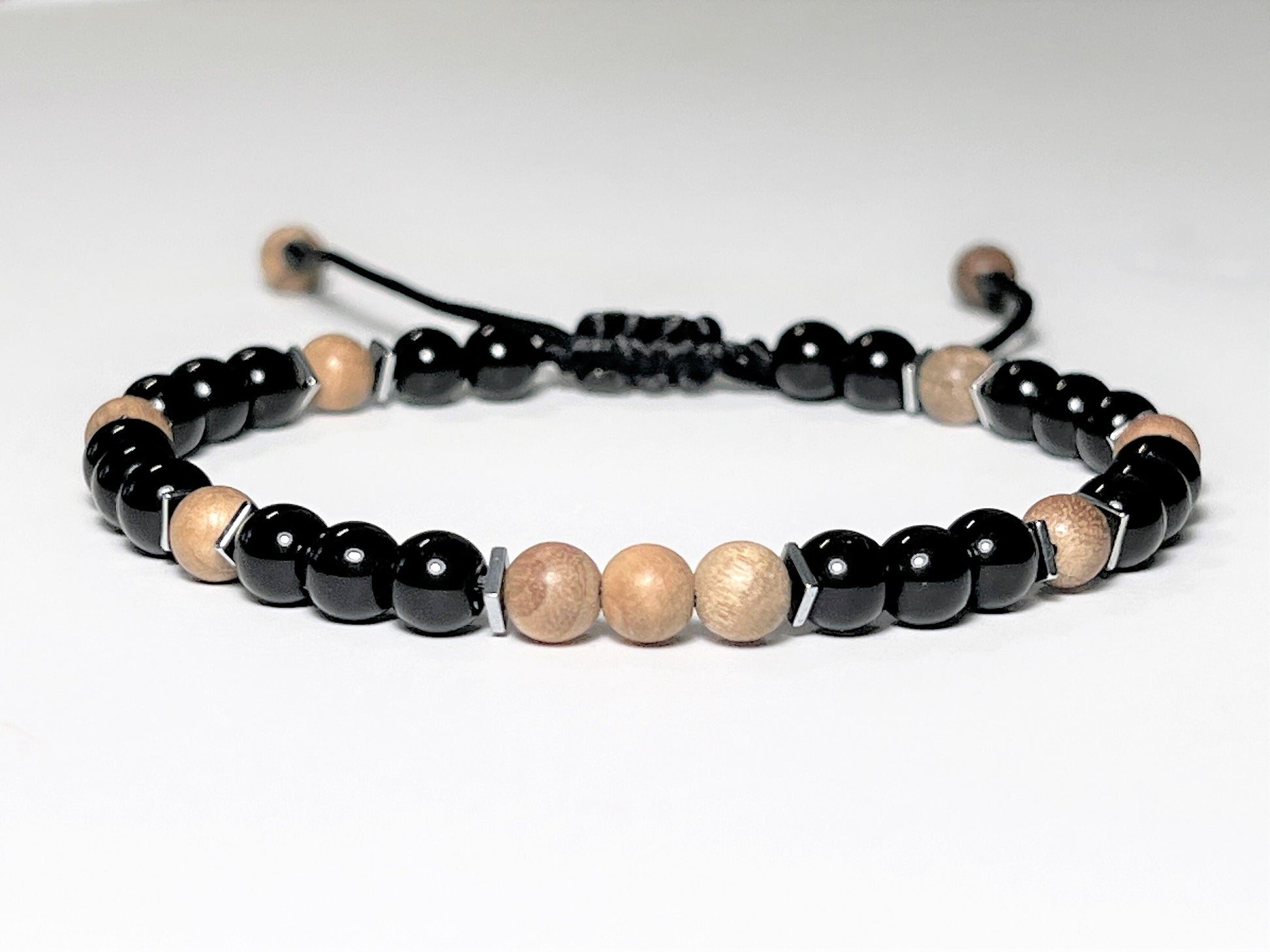 Round beaded Sandalwood Bracelet with black Onyx and a touch of Hematite square flat beads around Sandalwood beads. Round beads are 6mm. Waterproof and easily adjustable with a sliding macrame clasp. Round beads are 6 mm. Great gift for Boyfriend.