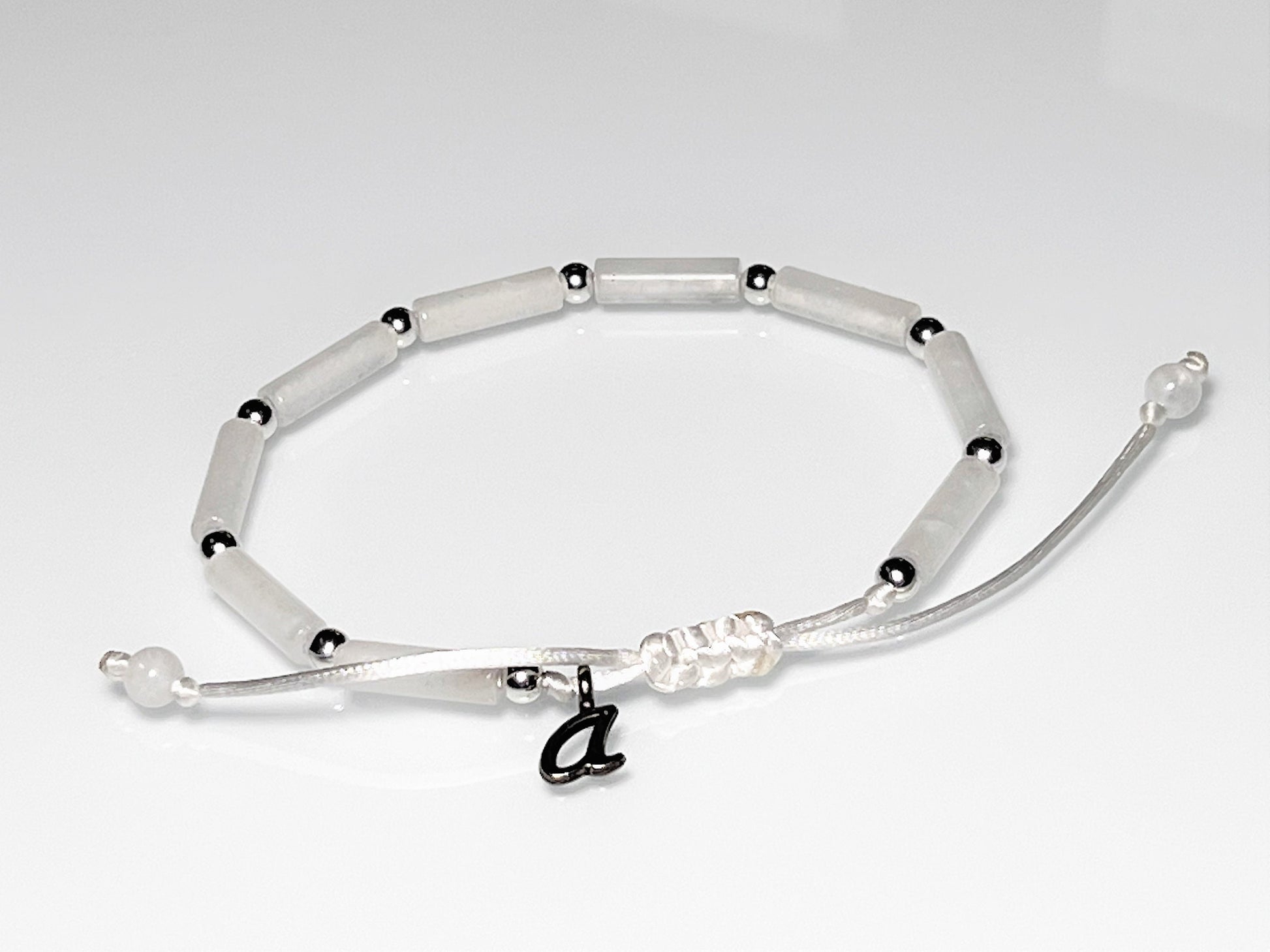 Initial personalized White jade tube bead bracelet with silver accents on an adjustable white cord.