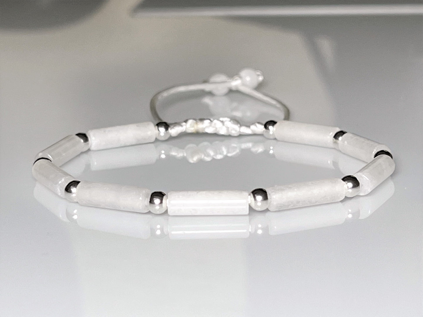 White jade and silver beaded bracelet on an adjustable cord, styled for a bride.