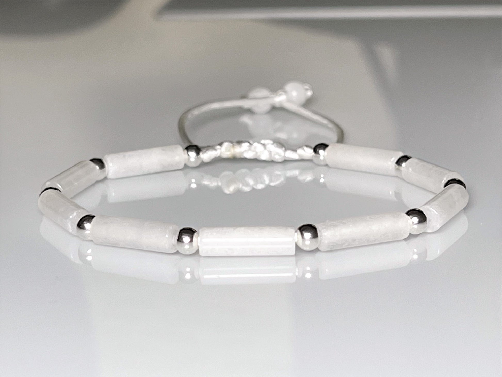 White jade and silver beaded bracelet on an adjustable cord, styled for a bride.