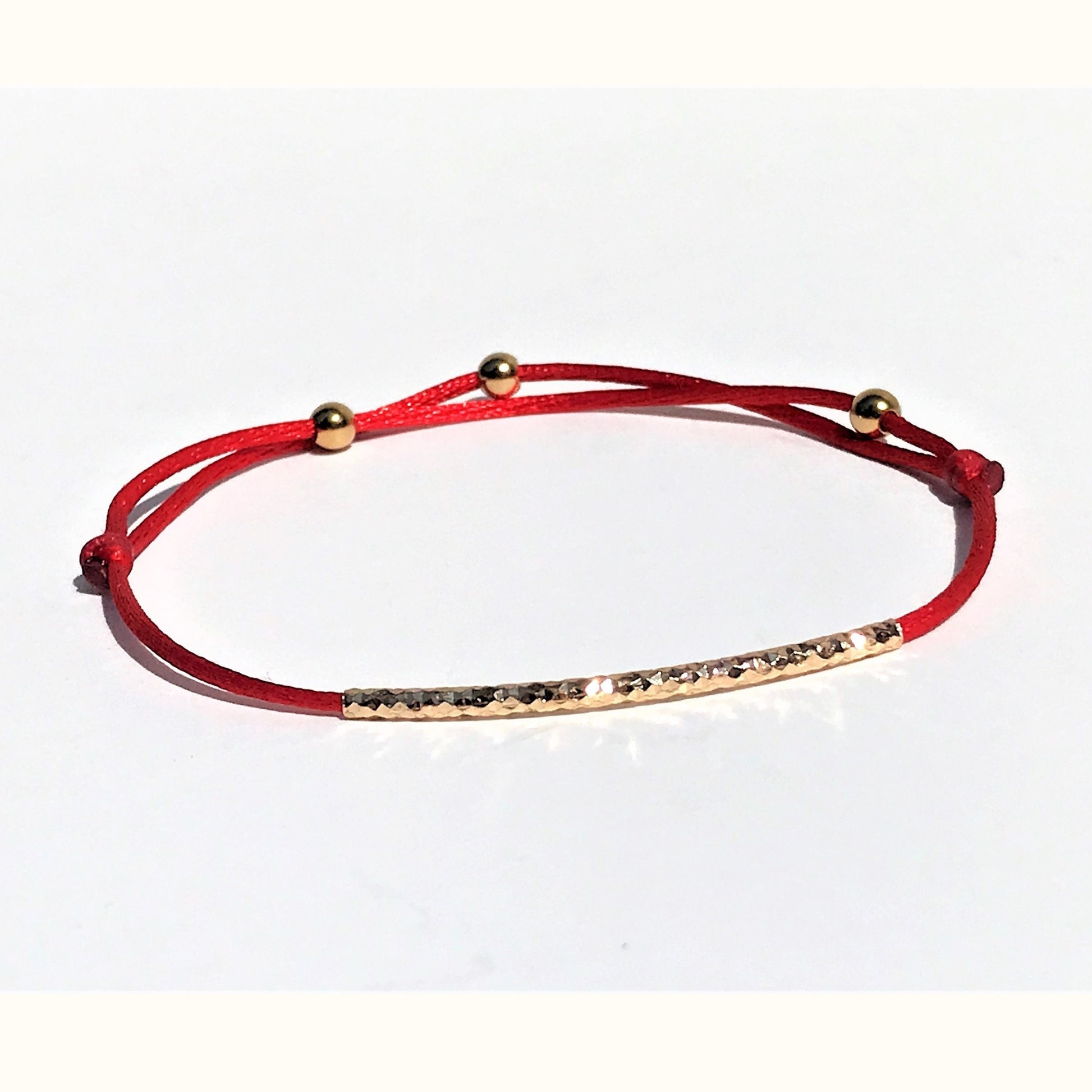 Handcrafted Adjustable Tiny Red String Bracelet for Good Luck. It features a silky red string complemented by a faced gold tube and 3 delicate beads. Personalize it with 1 initial charm—a perfect blend of elegance and meaning.