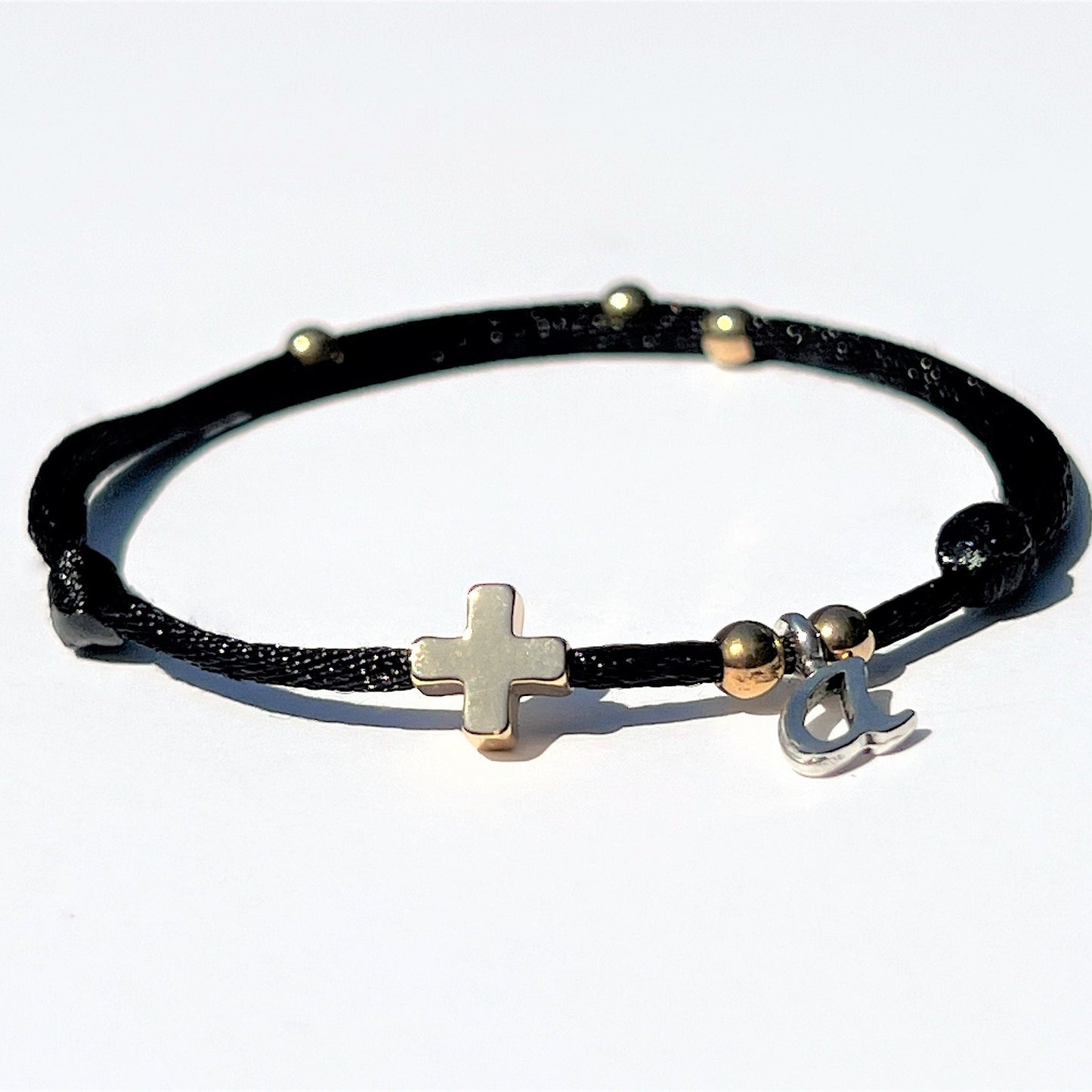 This Christian bracelet has a gold-filled cross on a silky nylon cord. 
 The bracelet can be personalized with an initial letter charm, making it suitable for men, women, and kids. The bracelet is easily adjustable and waterproof.