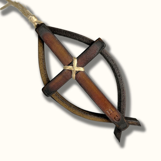 Handmade brown leather fish symbol ornament with a rustic leather cross tied at the center, hanging from a piece of natural twine.