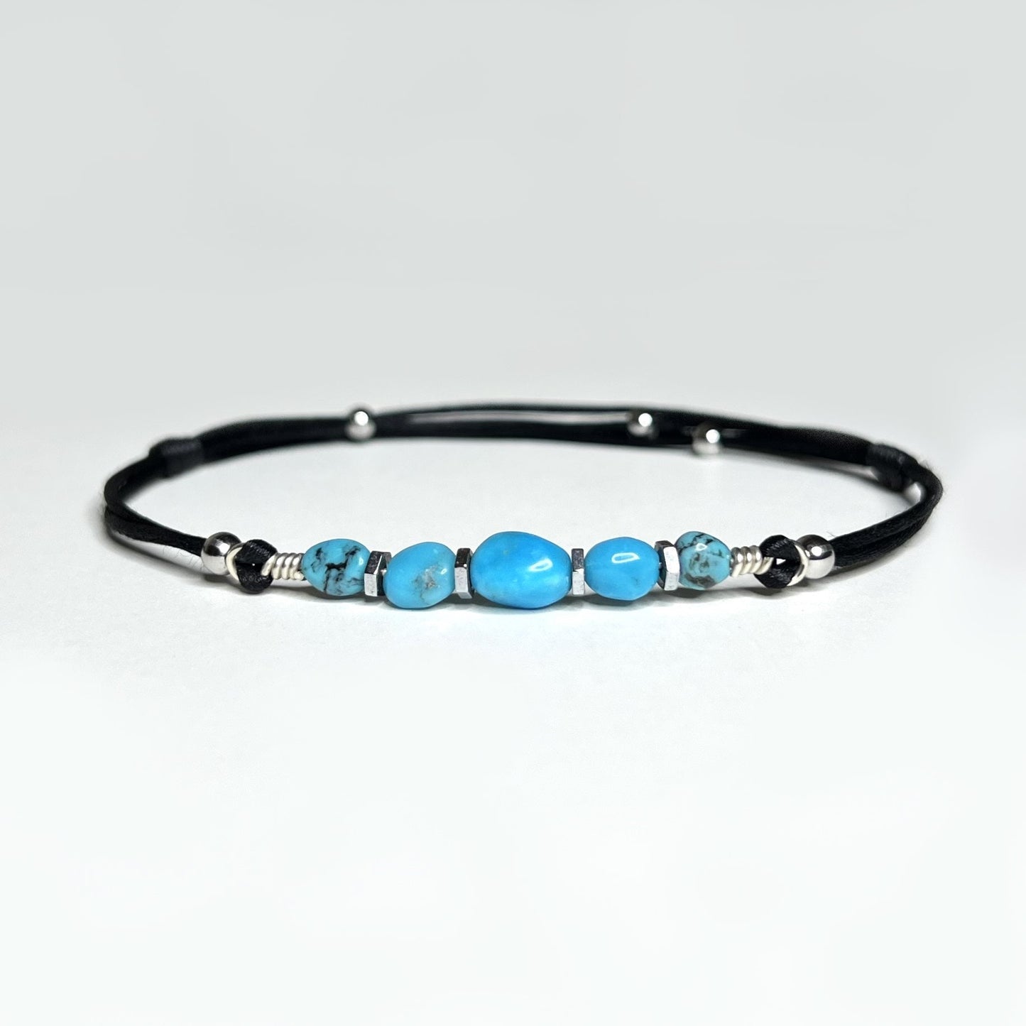 Adjustable and waterproof anklet. I use natural, untreated Turquoise nuggets and silver hematite beads on a black, silky nylon cord. A total of 5 gemstones,  in the center, a larger gemstone. Each stone is embellished with hematite beads around it.