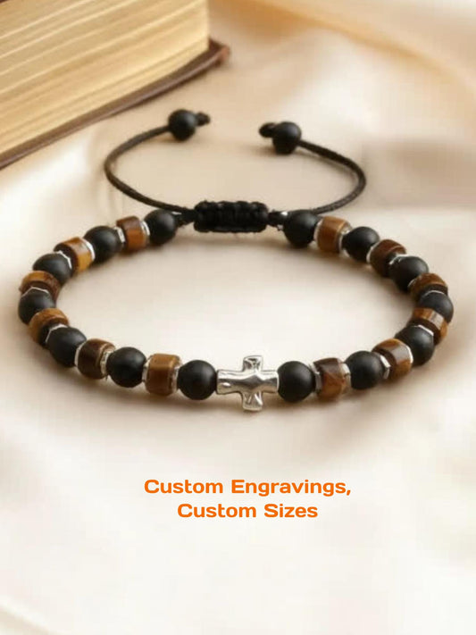 Handmade Christian bracelet featuring matte black onyx beads, golden tiger’s eye heishi beads, and silver hematite spacers with a silver cross centerpiece that can be personalized with engravings. The bracelet is strung on a black adjustable nylon cord, giving it a bold and masculine look. Designed as waterproof everyday jewelry, it symbolizes strength, courage, balance, and faith. Comes in a gift box, suitable for men or women as a spiritual or Christian gift.