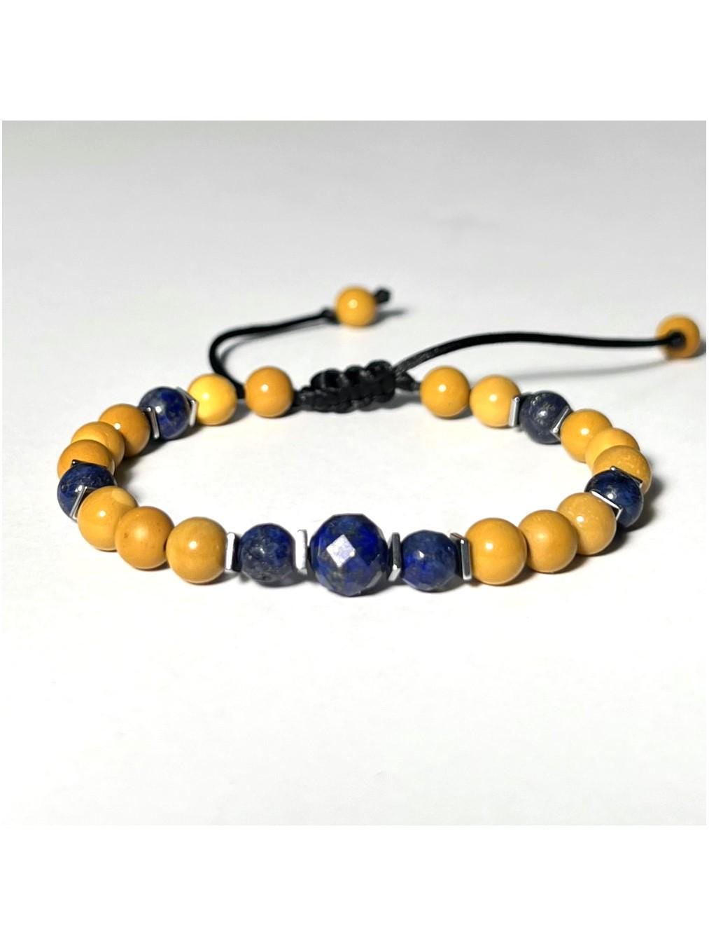Handmade unisex gemstone bracelet featuring round beads in rich yellow and blues. The bracelet showcases a symmetrical pattern of smooth and faceted natural yellow Mookaite Jasper beads, deep blue Lapis Lazuly beads, and shiny silver-toned square Hematite spacers. The centerpiece includes three larger faceted Lapis beads accented by tiny Hematite squares. All beads are strung on a durable black silky nylon cord with an adjustable sliding macramé clasp, finished with two bead-tipped cord ends.