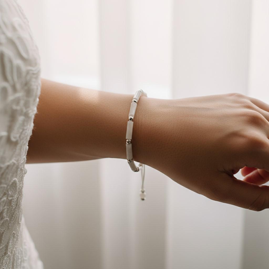Close-up of a wrist wearing a Delicate bracelet with white jade tube beads and silver accents on an adjustable white cord.