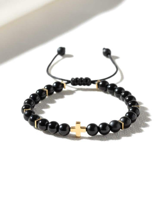 Adjustable black onyx bracelet with an 18k gold-filled cross charm, gold hematite spacers, and a sliding knot closure.