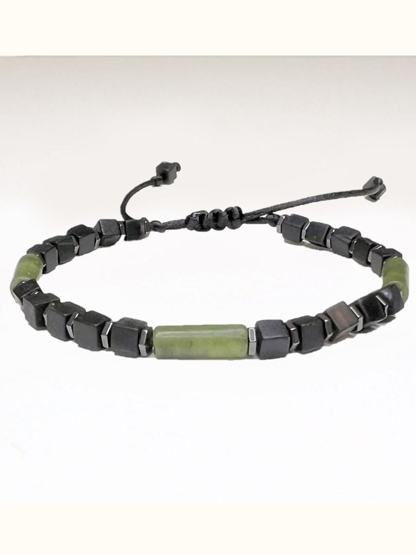 A handcrafted adjustable bracelet made with matte black cube beads and polished green jade stones. The design features three rounded green jade tube beads near the ends and one at the center. Black matte square beads with a subtle sheen are strung on a black cord in between the jade stones. The bracelet has a sliding knot closure for a flexible fit, and the materials give it a bold, modern, and slightly rugged look. It is suitable for men or women and can include a small initial charm.