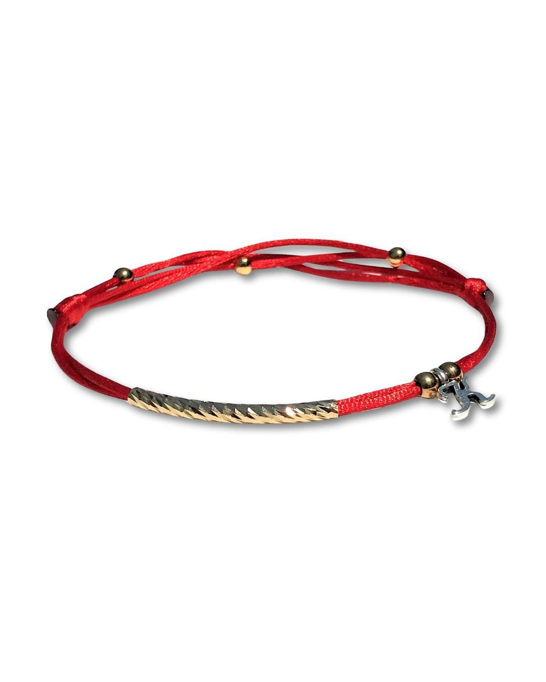 A red good-luck bracelet made from waterproof cord, featuring an adjustable sliding-knot design. The bracelet includes small 18K gold-filled round beads and a textured 18K gold-filled curved tube as the main accent. A small silver-tone initial charm hangs near the closure, allowing personalization with any letter. The bracelet is lightweight, minimalist, and photographed on a clean white background with soft shadows.