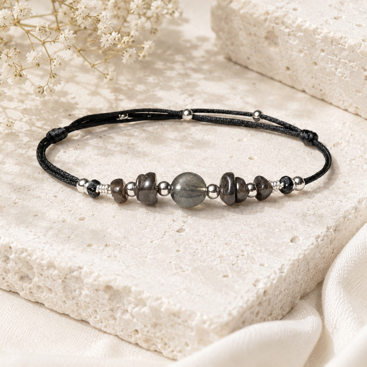 Adjustable black silky nylon cord with Labradorite gemstones on a real silver wire. In the middle of the anklet, one statement gemstone is surrounded by smaller Labradorite gemstones and embellished with tiny stainless steel round beads.