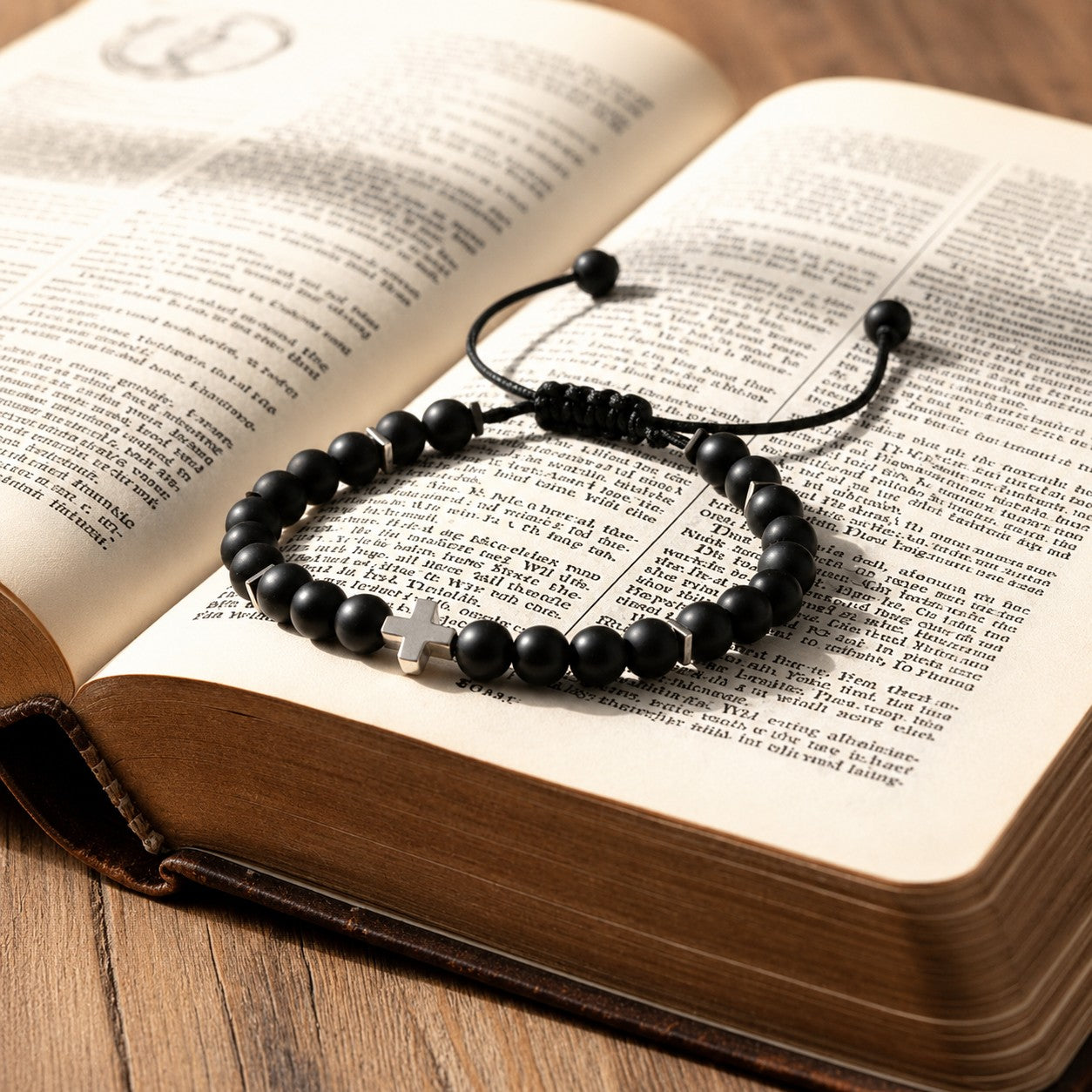 Adjustable black onyx bracelet with an 18k gold-filled cross charm, gold hematite spacers, and a sliding knot closure.