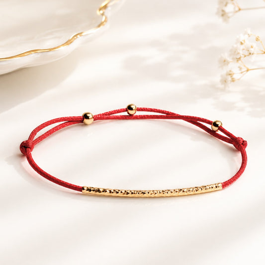 Handcrafted Adjustable Tiny Red String Bracelet for Good Luck. It features a silky red string complemented by a faceted gold tube and 3 delicate beads. Personalize it with 1 initial charm—a perfect blend of elegance and meaning.