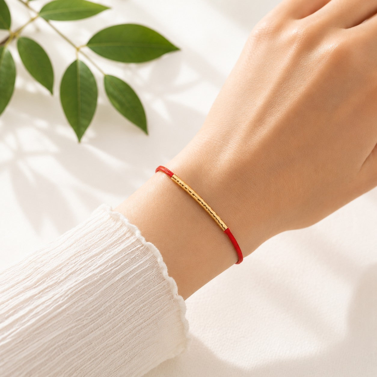 Handcrafted Adjustable Tiny Red String Bracelet for Good Luck. It features a silky red string complemented by a faceted gold tube and 3 delicate beads. Close-up of a person wearing a red string bracelet on their wrist.