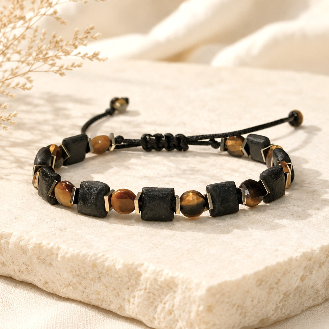 Square natural matte black agate beads, with faceted round tiger eye, create an adjustable bracelet for both men and women. Embellished with tiny flat gold hematite beads, this bracelet offers triple protection and brings its owner luck, prosperity, and happiness.y, and happiness.